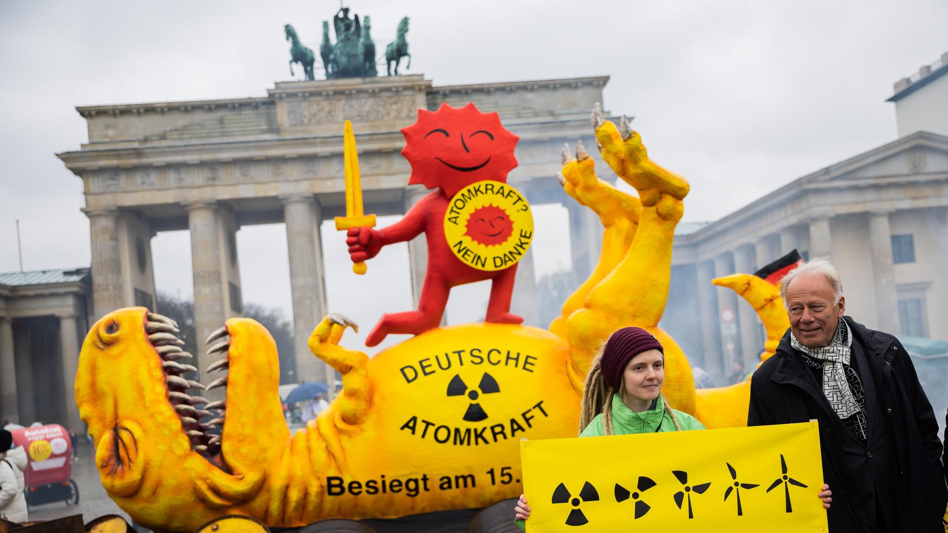 Jürgen Trittin (Bündnis 90/Die Grünen), Mitglied des Deutschen Bundestages und ehemaliger Umweltminister, steht neben einer Aktivistin vor einer Dinosaurier-Figur und der roten Sonne, teil des Anti-Atomkraft-Logos, bei einer Aktion der Umweltorganisation Greenpeace vor dem Brandenburger Tor. Jürgen Trittin (Bündnis 90/Die Grünen), Mitglied des Deutschen Bundestages und ehemaliger Umweltminister, steht neben einer Aktivistin vor einer Dinosaurier-Figur und der roten Sonne, teil des Anti-Atomkraft-Logos, bei einer Aktion der Umweltorganisation Greenpeace vor dem Brandenburger Tor.