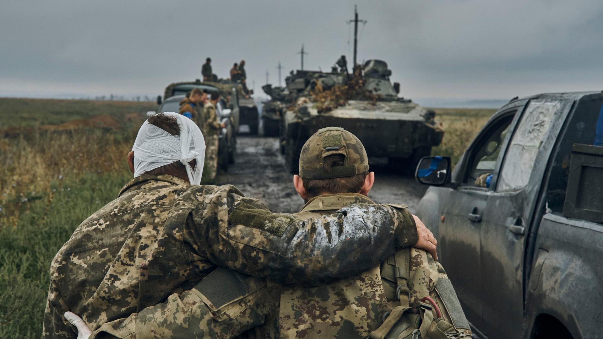 Das Foto zeigt, wie ein ukrainischer Soldat einem verletzten anderen Soldaten hilft.