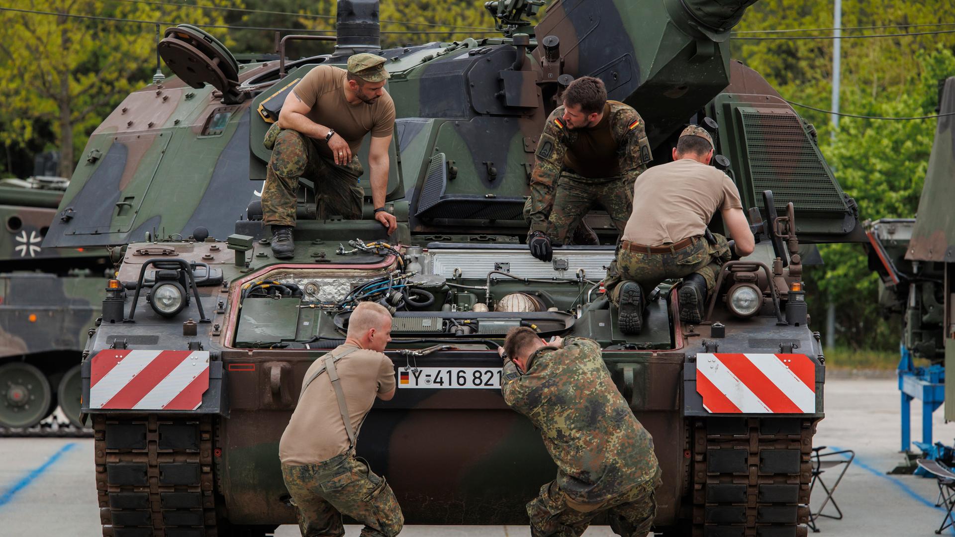 Eine Gruppe von fünf Soldaten arbeiten an einem Panzer. Eine Gruppe von fünf Soldaten arbeiten an einem Panzer.