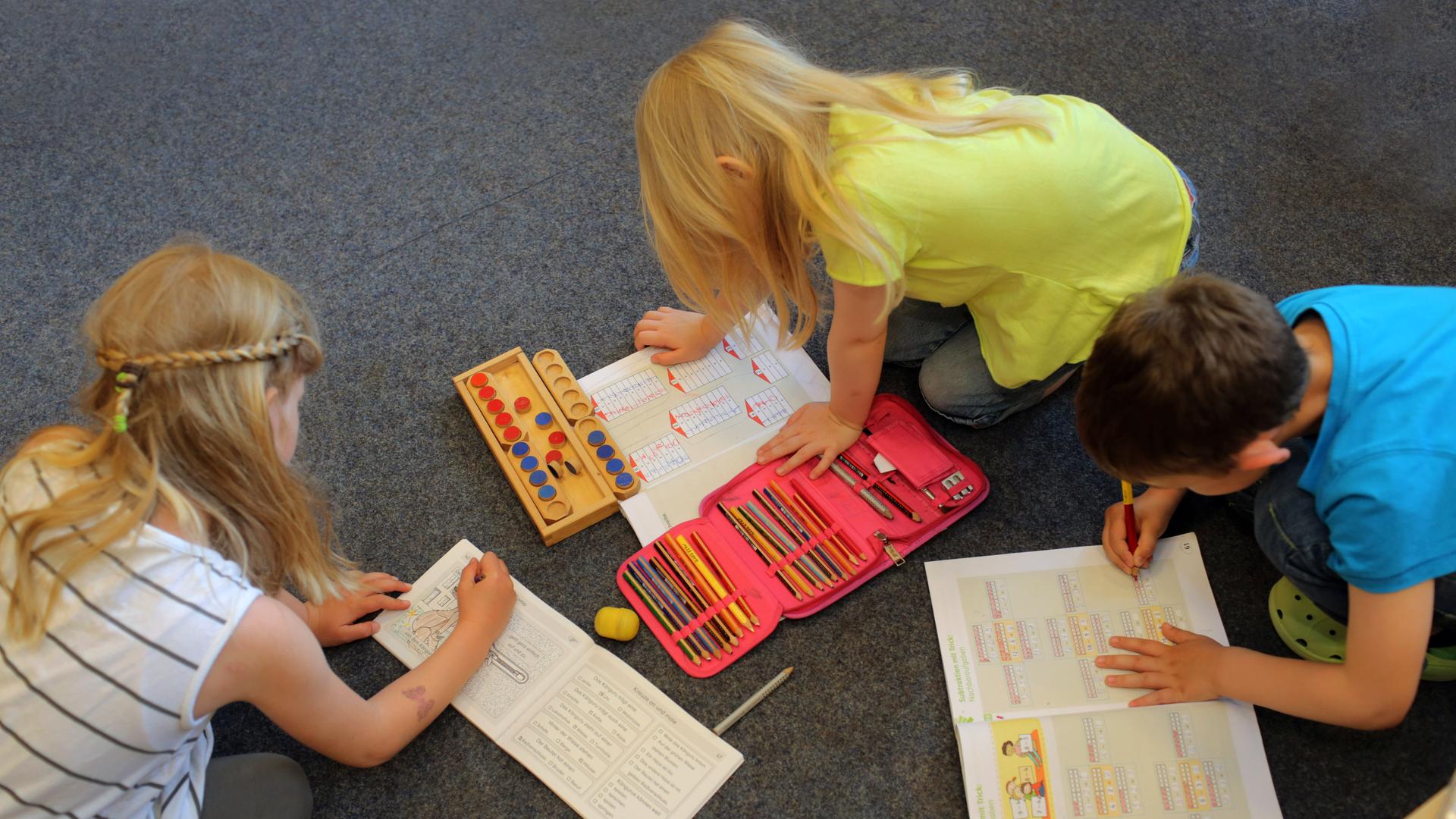 Kinder lernen spielerisch auf dem Boden ihres Klassenzimmers 