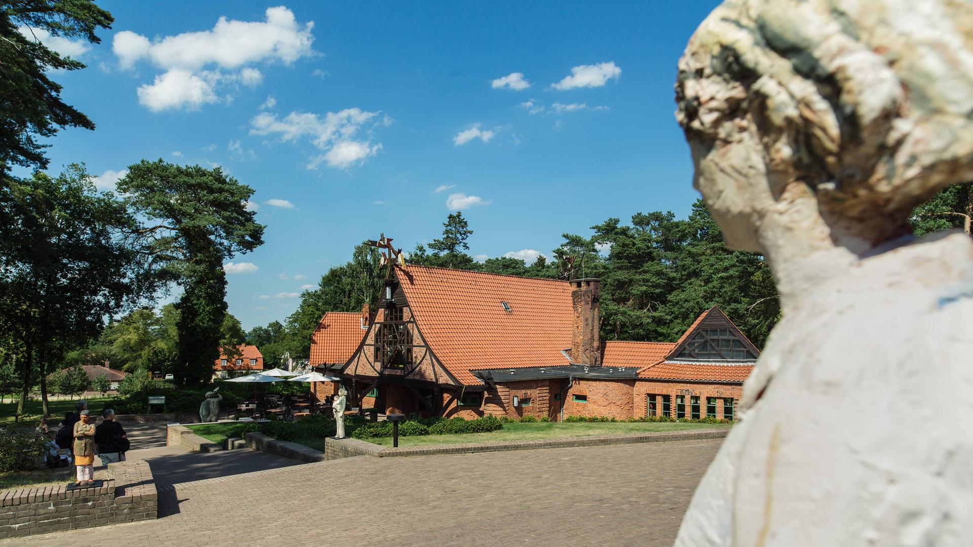 Rote Backsteingebäude in der Künstlerkolonie Worpswede von grünen Bäumen umgeben, vor blauem, fast wolkenlosem Himmel. Rote Backsteingebäude in der Künstlerkolonie Worpswede von grünen Bäumen umgeben, vor blauem, fast wolkenlosem Himmel.