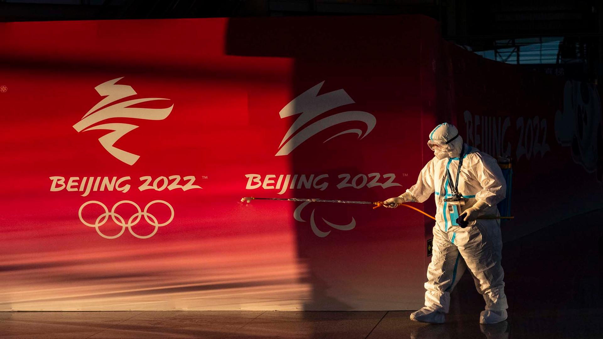 Ein Mann am Pekinger Flughafen desinfiziert vor dem Olympia Logo Flächen. 
