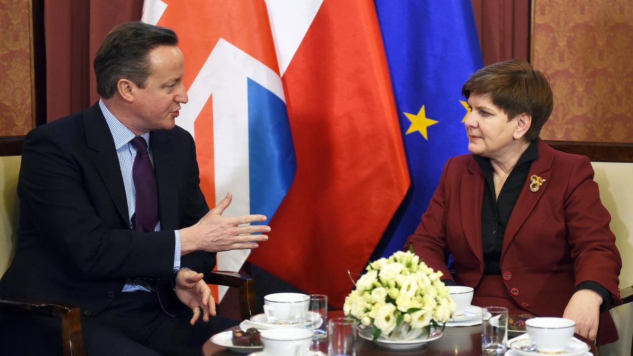 Cameron und Szydlo sitzen gemeinsam vor den Flaggen ihrer Länder.