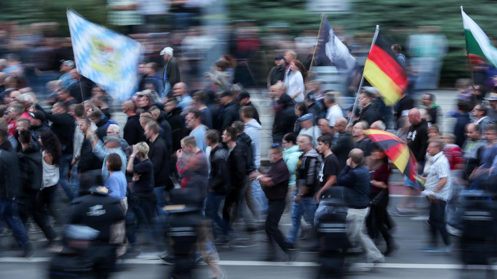 27.08.2018, Sachsen, Chemnitz: Demonstranten der rechten Szene schwenken Deutschlandfahnen und tragen einen Regenschirm in Deutschlandfarben. Nach einem Streit war in der Nacht zu Sonntag in der Innenstadt von Chemnitz ein 35-jähriger Mann erstochen worden. Die Tat war Anlass für spontane Demonstrationen, bei denen es auch zu Jagdszenen und Gewaltausbrüchen kam. 27.08.2018, Sachsen, Chemnitz: Demonstranten der rechten Szene schwenken Deutschlandfahnen und tragen einen Regenschirm in Deutschlandfarben. Nach einem Streit war in der Nacht zu Sonntag in der Innenstadt von Chemnitz ein 35-jähriger Mann erstochen worden. Die Tat war Anlass für spontane Demonstrationen, bei denen es auch zu Jagdszenen und Gewaltausbrüchen kam.