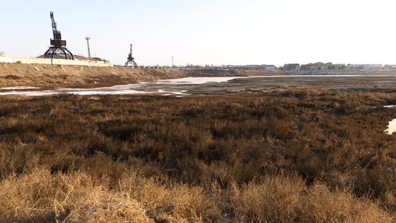 Das leere Hafenbecken in Aralsk. Hier legten vor 50 Jahren Schiffe an. Heute wachsen Pflanzen im Sand. Die alten Kräne sind noch zu sehen. Das leere Hafenbecken in Aralsk. Hier legten vor 50 Jahren Schiffe an. Heute wachsen Pflanzen im Sand. Die alten Kräne sind noch zu sehen.