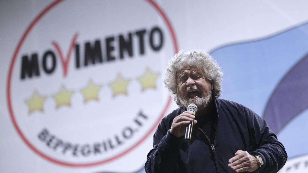 Beppe Grillo, Gründer der "Fünf-Sterne-Bewegung", spricht auf einer Wahlkampfveranstaltung. Im Hintergrund das Logo seiner Partei.