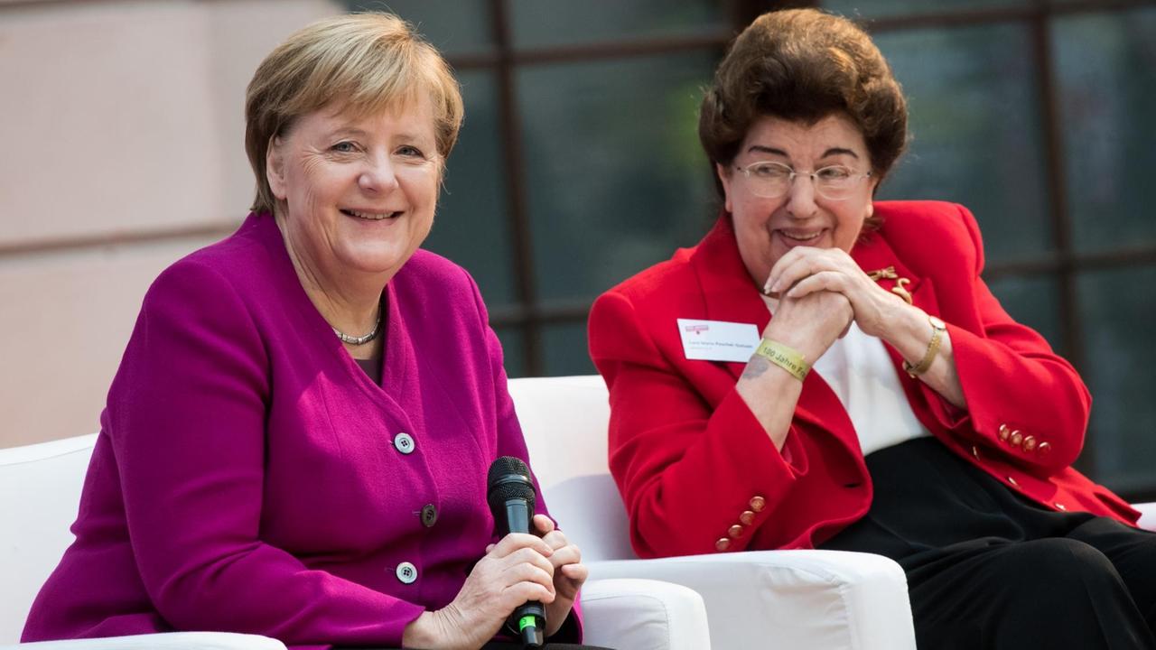 Bundeskanzlerin Angela Merkel und Lore Peschel-Gutzeit sitzen bei einer Podiumsdiskussion beim Festakt zu 100 Jahre Frauenwahlrecht im Deutschen Historischen Museum zusammen.