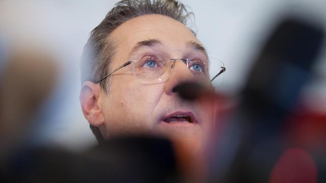 Österreichs ehemaliger Vizekanzler und Ex-FPÖ-Chef Strache halbverdeckt durch Mikrophone, in Nahaufnahme.