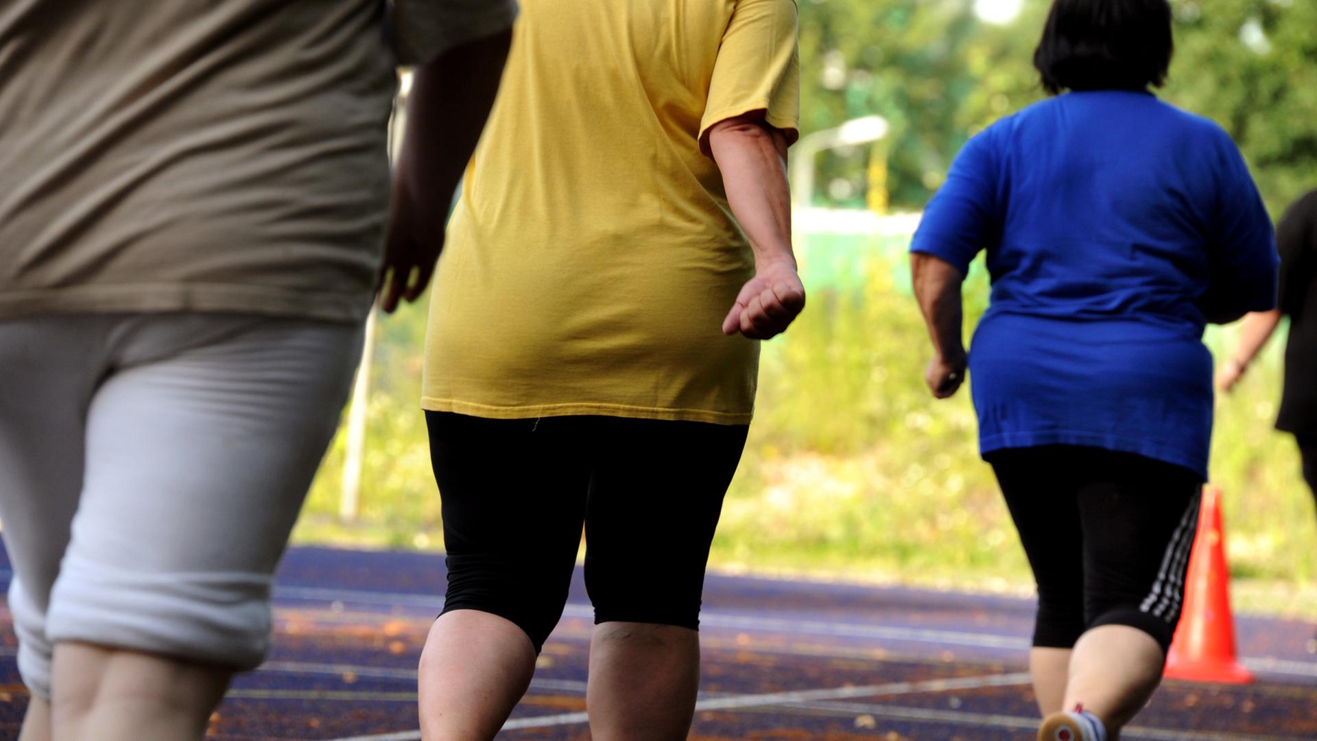 Übergewichtige Frauen und Männern bei Ausdauerübungen auf einem Sportplatz Übergewichtige Frauen und Männern bei Ausdauerübungen auf einem Sportplatz