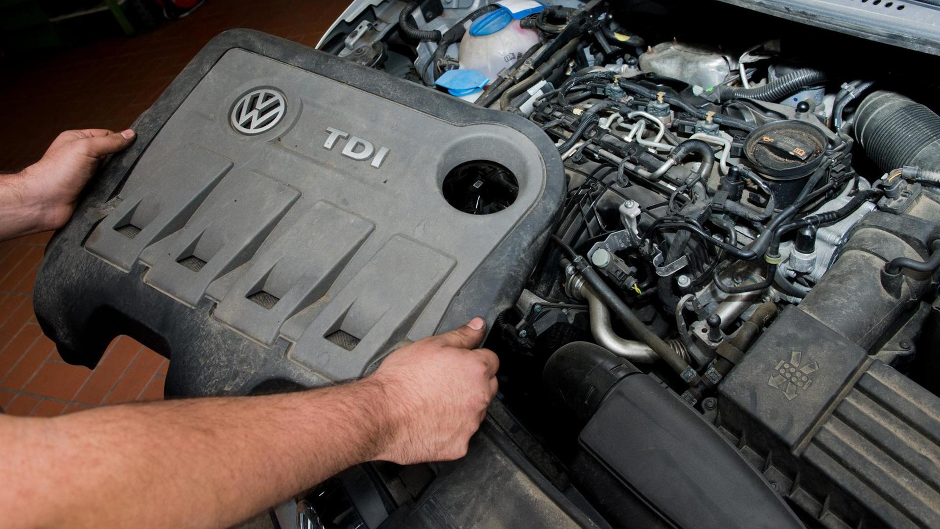 Ein KFZ-Servicetechniker hält am 08.10.2015 die Abdeckung vor einem vom Abgas-Skandal betroffenen 2.0l TDI Dieselmotor vom Typ EA189 in einem VW Touran in einer Autowerkstatt in Hannover (Niedersachsen). Ein KFZ-Servicetechniker hält am 08.10.2015 die Abdeckung vor einem vom Abgas-Skandal betroffenen 2.0l TDI Dieselmotor vom Typ EA189 in einem VW Touran in einer Autowerkstatt in Hannover (Niedersachsen).