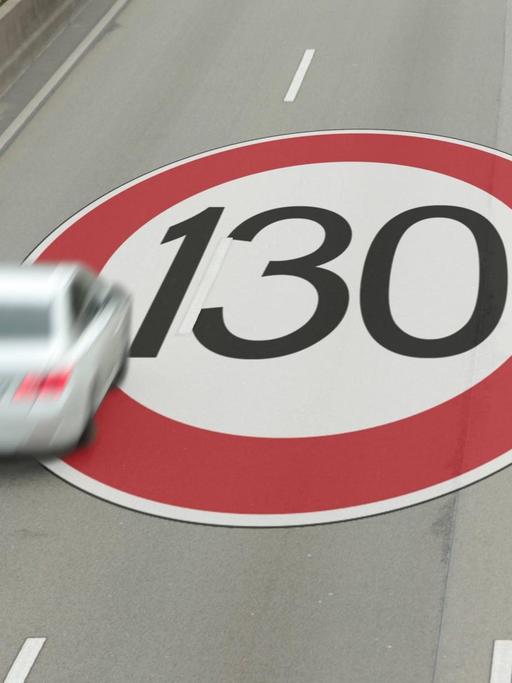 Symbolbild für ein Tempolimit auf Autobahnen: Blick von oben auf ein Fahrzeug auf der linken Spur. Auf der Fahrbahn ist ein Schild für eine Höchstgeschwindigkeit von 130 zu sehen.