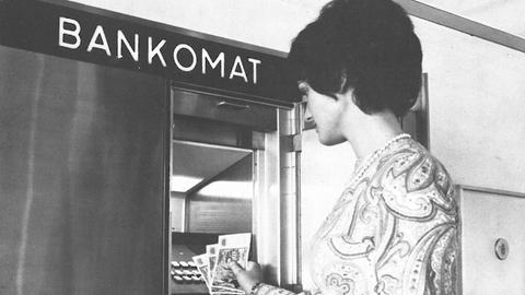 Eine Bank-Kundin hebt 1971 an einem "Bankomat" Bargeld ab