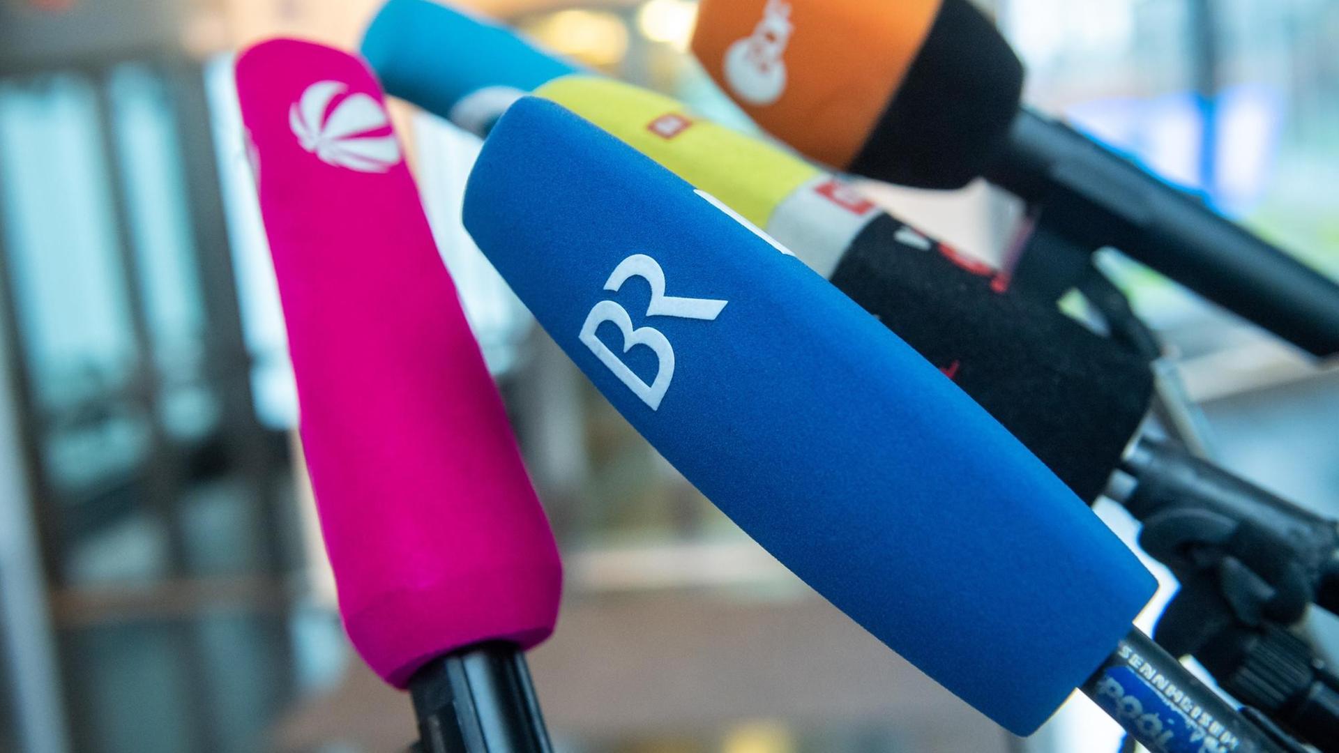 Diverse Mikrofone von öffentlichen und privaten Fernsehsendern stehen zu Beginn einer Pressekonferenz nebeneinander.