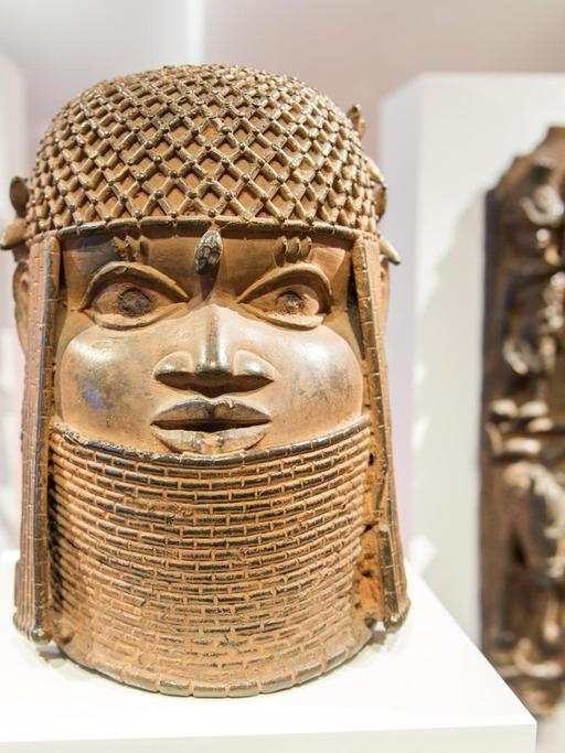 Eine afrikanische Plastik in der Mitte scheint den Betrachter anzublicken, links und rechts sind zwei weitere schemenhaft zu erkennen.