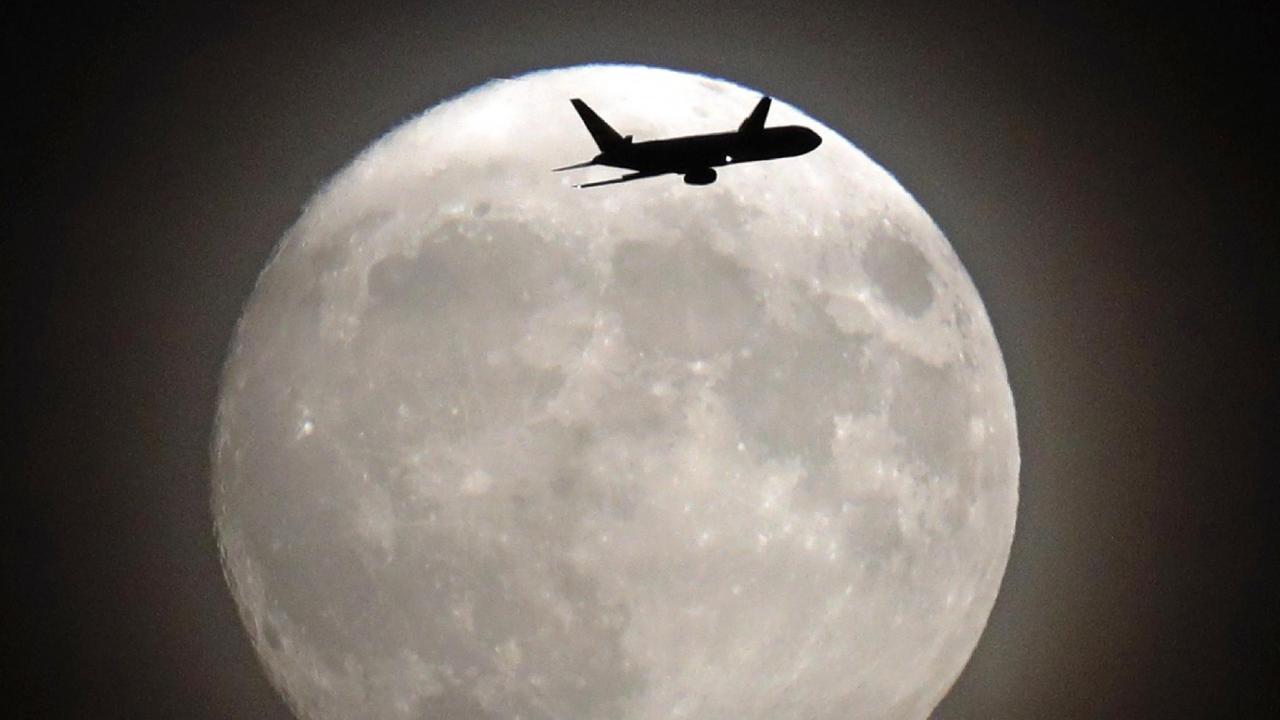 Ein große Vollmond, vor dem sich ein Passagierflugzeug abhebt. Ein große Vollmond, vor dem sich ein Passagierflugzeug abhebt.