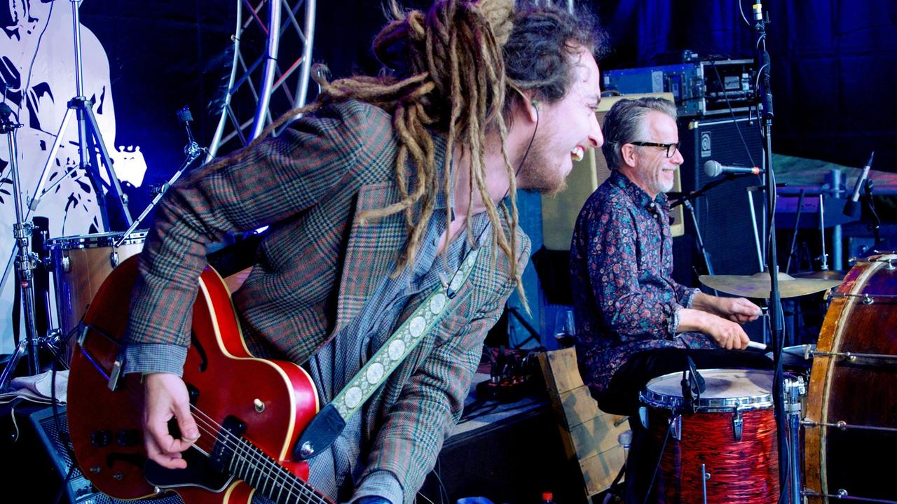 Ein Mann mit Gitarre und ein Mann am Schlagzeug machen Musik Ein Mann mit Gitarre und ein Mann am Schlagzeug machen Musik