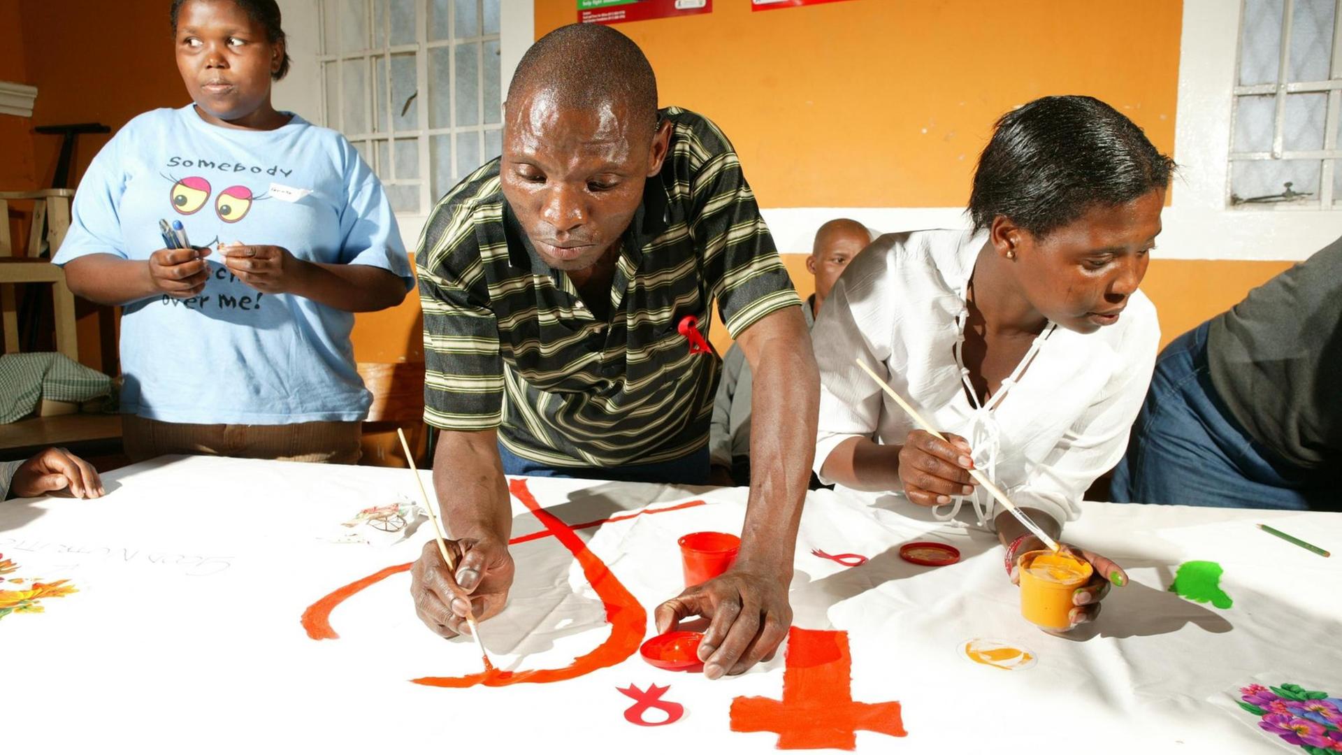 Ein Mann zeichnet "die rote Schleife" für die Präventionsarbeit gegen HIV/AIDS in Kapstadt in Südafrika, Afrika. Ein Mann zeichnet "die rote Schleife" für die Präventionsarbeit gegen HIV/AIDS in Kapstadt in Südafrika, Afrika.