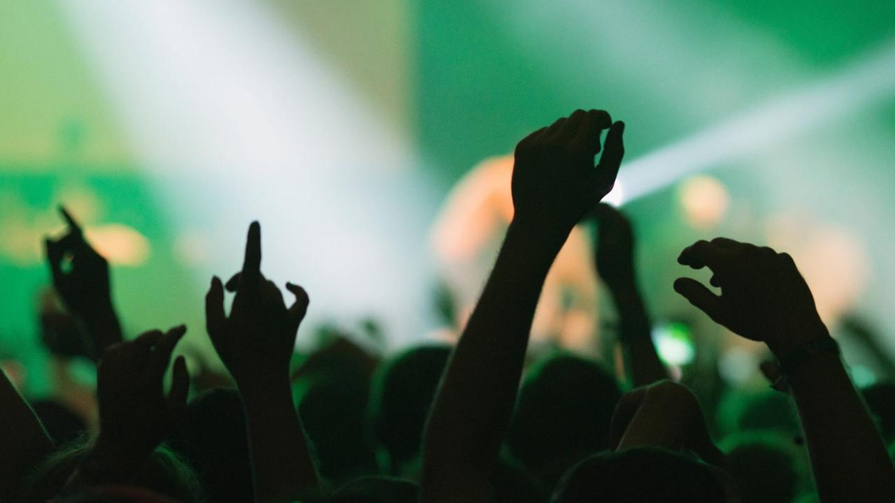 Back view silhouettes of people with hands up against illuminated with green lights stage during music performance Copyright: xRobertxKohlhuberx Back view silhouettes of people with hands up against illuminated with green lights stage during music performance Copyright: xRobertxKohlhuberx