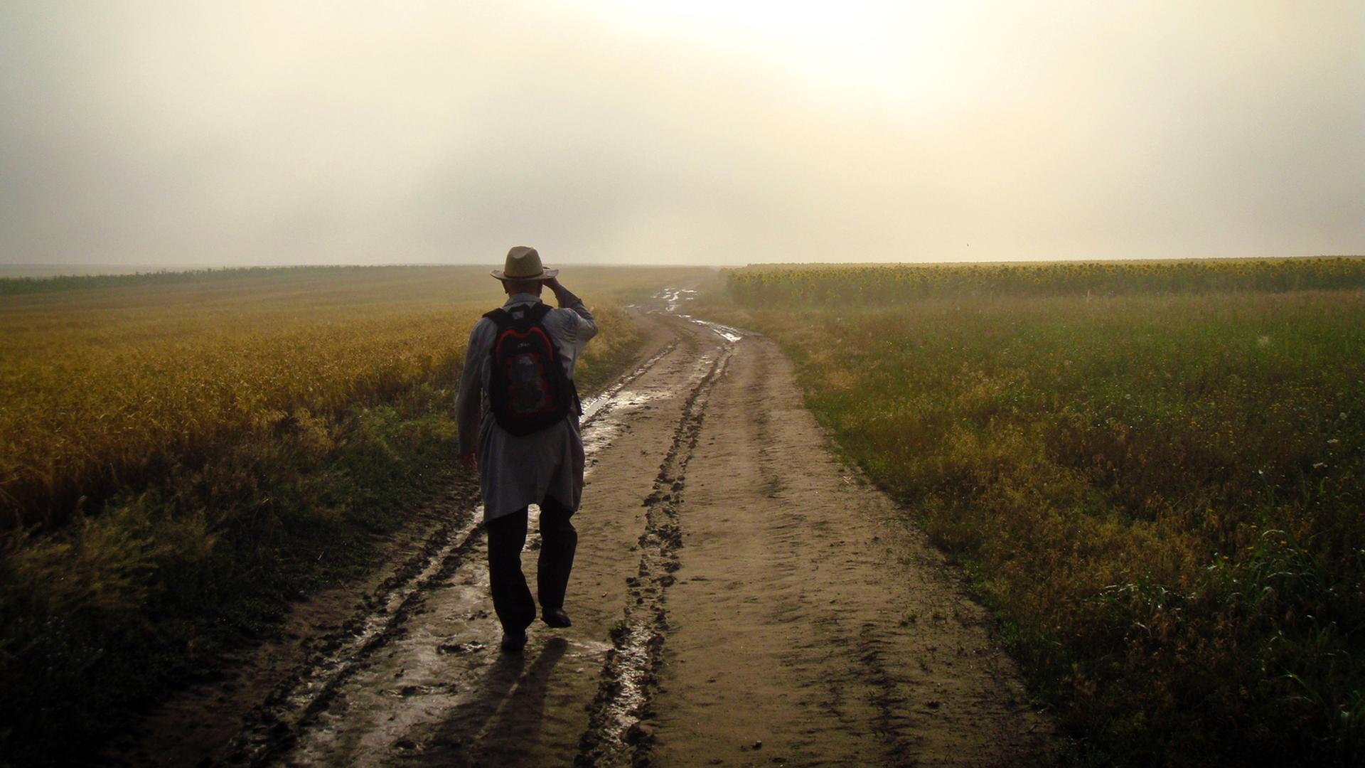 Ein Mann geht einen Feldweg entlang. Ein Mann geht einen Feldweg entlang.