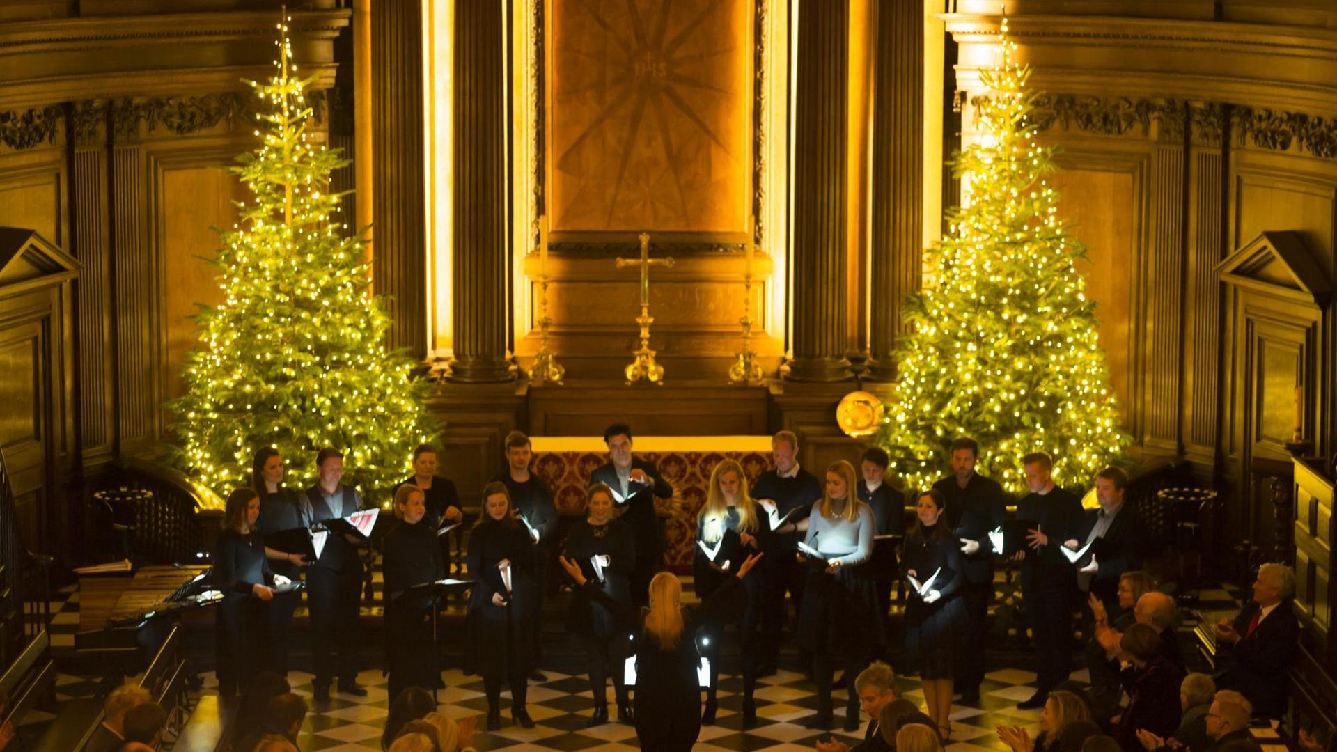 Zwischen zwei beschmückten und leuchtenden Weihnachtsbäumen steht das Ensemble Zwischen zwei beschmückten und leuchtenden Weihnachtsbäumen steht das Ensemble