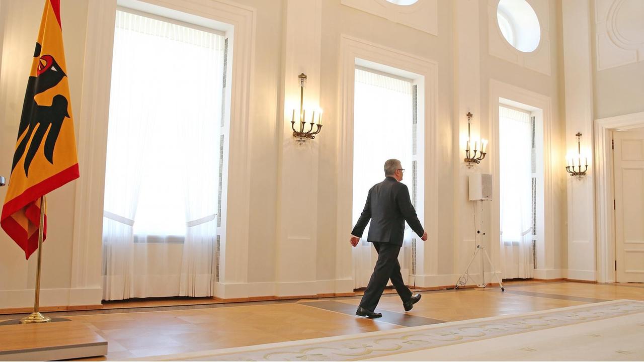 Bundespräsident Joachim Gauck schreitet durch einen großen Saal auf zwei Flügeltüren zu, mit dem Rücken zum Betrachter.