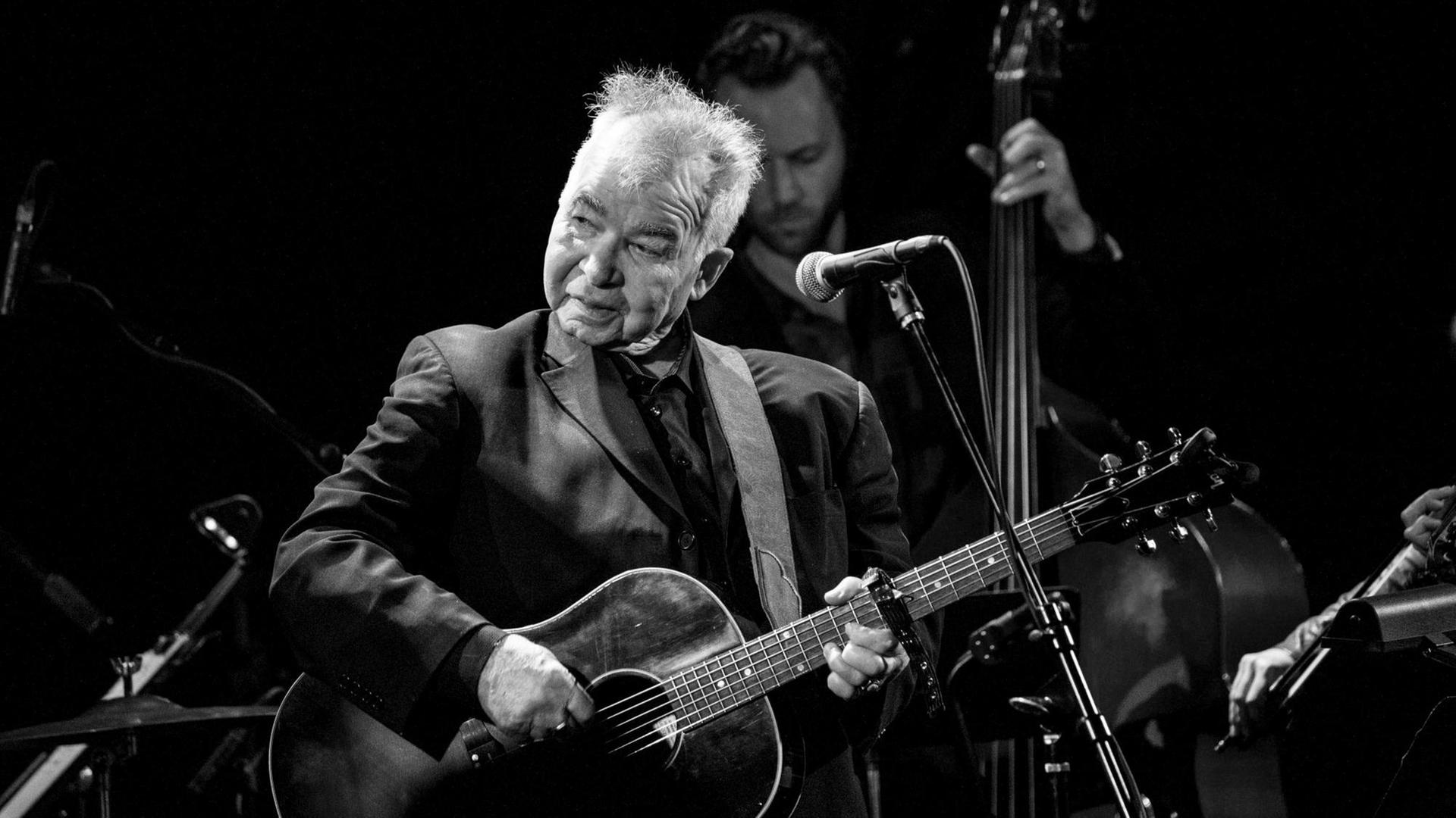 Aufnahme von Musiker John Prine auf der Bühne mit Gitarre. Aufnahme von Musiker John Prine auf der Bühne mit Gitarre.