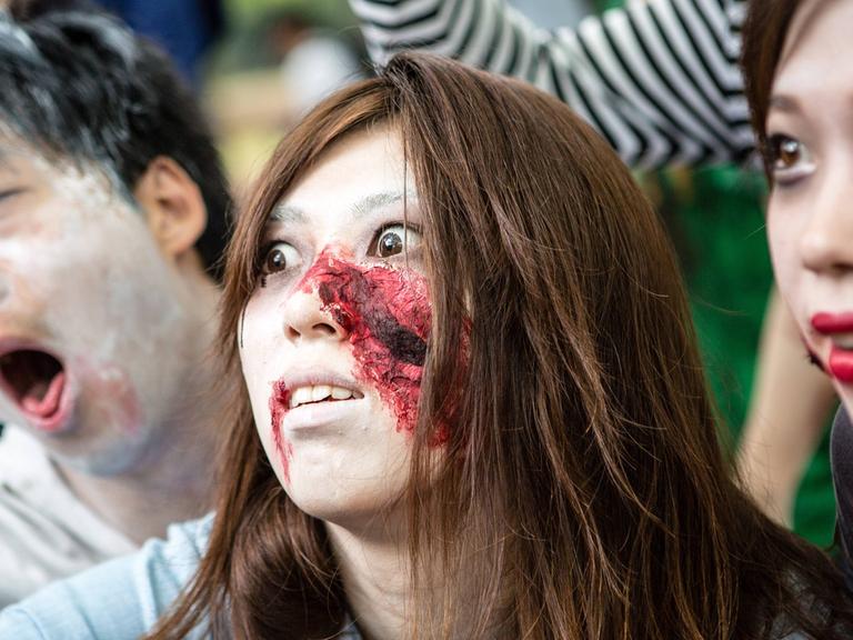 Zu sehen sind als Zombies verkleidete und geschminkte Menschen bei einem Zombie Walk
