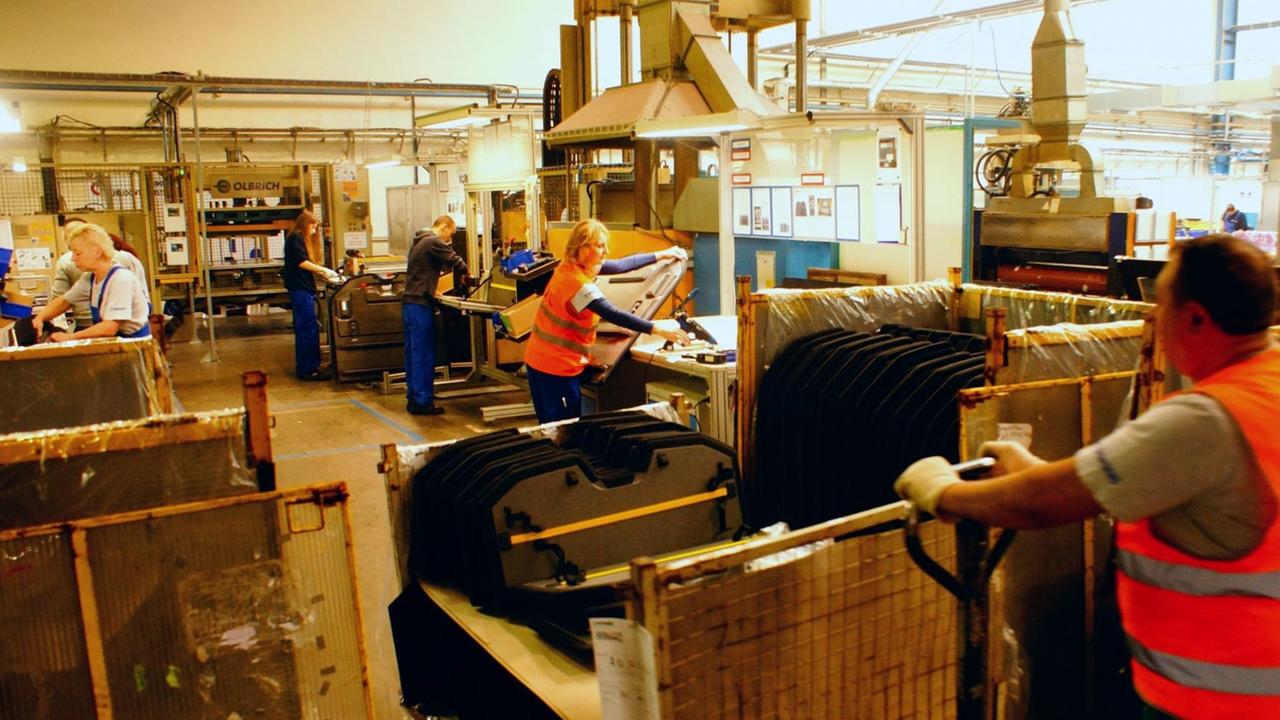 Mehrere Arbeiter in einer Fabrikhallte stehen an ihren Maschinen. Mehrere Arbeiter in einer Fabrikhallte stehen an ihren Maschinen.