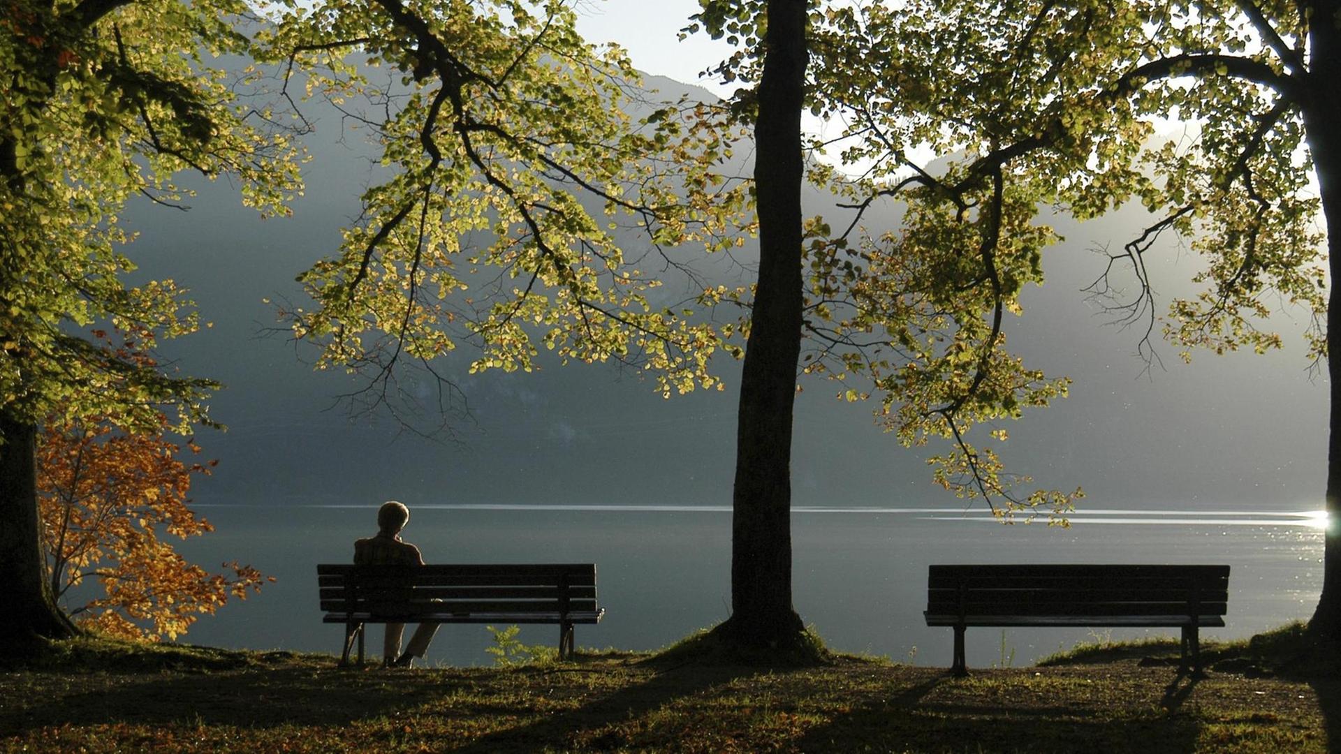 Alter Mann auf einer Parkbank am Kochelsee in Bayern. Alter Mann auf einer Parkbank am Kochelsee in Bayern.