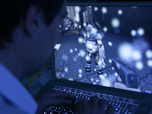 Ein junger Mann sitzt vor seinem Computer und spielt ein Computerspiel.