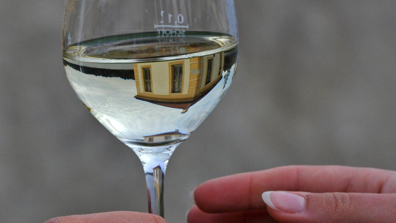 In einem Glas Weißwein spiegelt sich in Moritzburg in Sachsen ein Teehaus am Jagdschloss. In einem Glas Weißwein spiegelt sich in Moritzburg in Sachsen ein Teehaus am Jagdschloss.