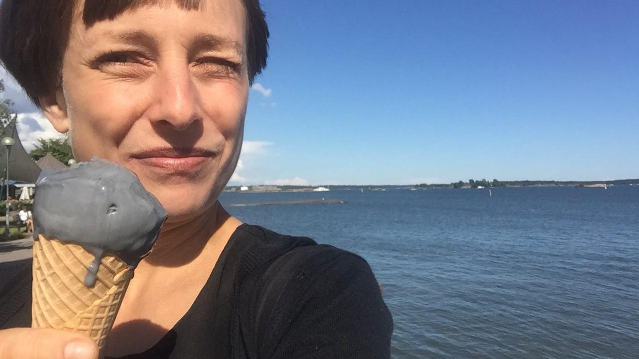 Reporterin Jenni Roth in Finnland am Meer mit grauem Salmiakeis.