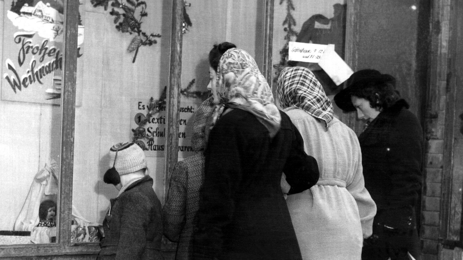 Passanten betrachten in der Vorweihnachtszeit 1945 das weihnachtlich dekorierte Schaufenster eines Geschäftes in Frankfurt am Main. Kurz nach Kriegsende versucht die Frankfurter Geschäftswelt trotz Bombenschäden und leerer Regale die Bevölkerung mit bescheidenen Mitteln auf die Weihnachtszeit einzustimmen. Passanten betrachten in der Vorweihnachtszeit 1945 das weihnachtlich dekorierte Schaufenster eines Geschäftes in Frankfurt am Main. Kurz nach Kriegsende versucht die Frankfurter Geschäftswelt trotz Bombenschäden und leerer Regale die Bevölkerung mit bescheidenen Mitteln auf die Weihnachtszeit einzustimmen.