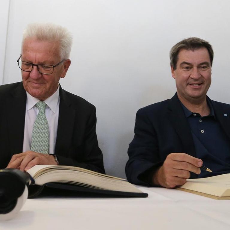 23.07.2019, Baden-Württemberg, Meersburg: Winfried Kretschmann, Ministerpräsident von Baden-Württemberg (Grüne,l) und Markus Söder, bayerischer Ministerpräsident (CSU) tragen sich in die Bücher der Stadt und des Landes ein. Foto: Karl-Josef Hildenbrand/dpa | Verwendung weltweit 23.07.2019, Baden-Württemberg, Meersburg: Winfried Kretschmann, Ministerpräsident von Baden-Württemberg (Grüne,l) und Markus Söder, bayerischer Ministerpräsident (CSU) tragen sich in die Bücher der Stadt und des Landes ein. Foto: Karl-Josef Hildenbrand/dpa | Verwendung weltweit