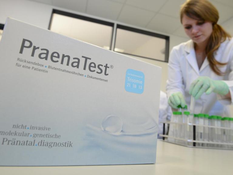 Eine Mitarbeiterin der Firma Lifecodexx ordnet Reagenzgläser. Im Vordergrund ist die Verpackung für den Trisomie-Bluttest der Firma zu sehen.