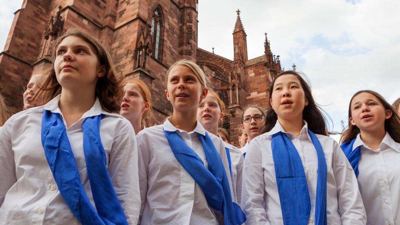 Mädchen mit weißer Bluse und blauem Halstuch vor dem Freiburger Münster. Mädchen mit weißer Bluse und blauem Halstuch vor dem Freiburger Münster.