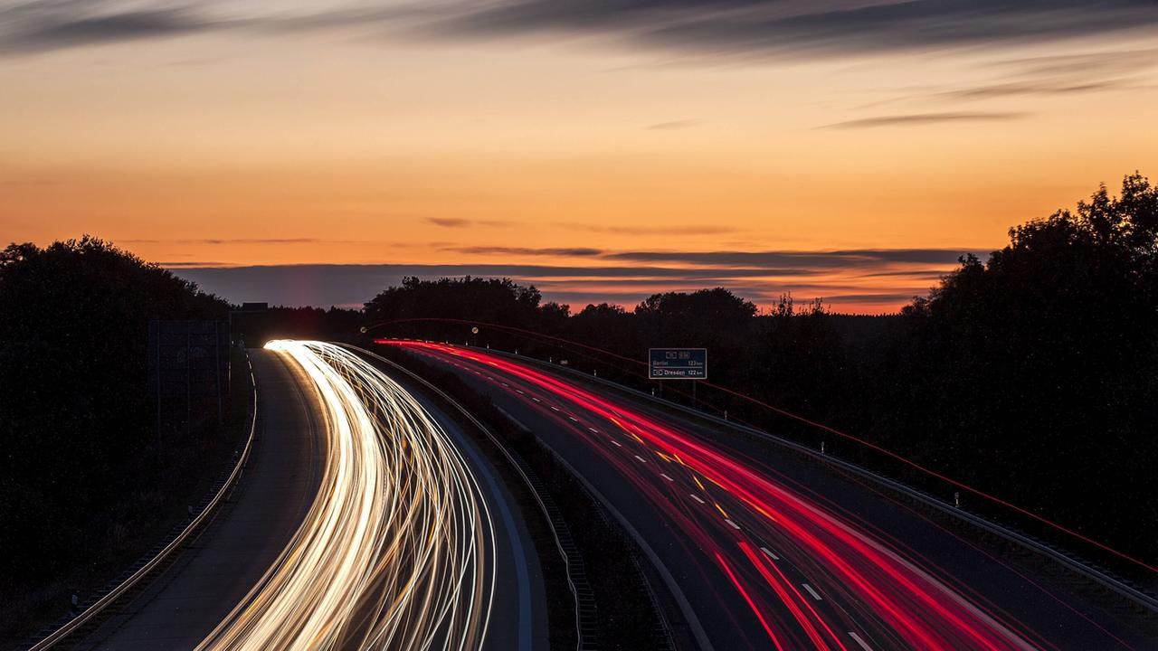 Die Sonne geht am Abend, den 03.10.2012 über der Bundesautobahn (BAB) A15 in der Nähe von Cottbus, Brandenburg in Deutschland unter. Die unzähligen Autos verschwimmen und erzeugen roten und gelben Lichtspuren. Die Sonne geht am Abend, den 03.10.2012 über der Bundesautobahn (BAB) A15 in der Nähe von Cottbus, Brandenburg in Deutschland unter. Die unzähligen Autos verschwimmen und erzeugen roten und gelben Lichtspuren.