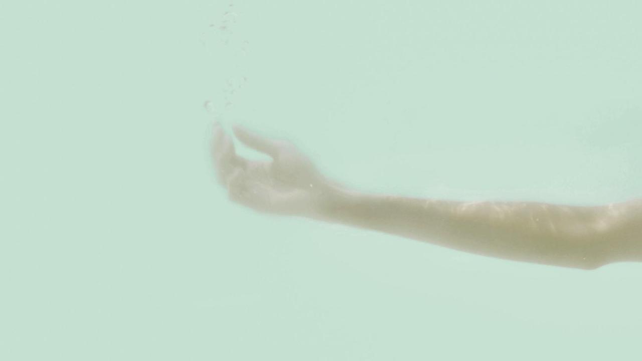 Ein Arm streckt sich vor blauem Hintergrund aus. Ein Arm streckt sich vor blauem Hintergrund aus.