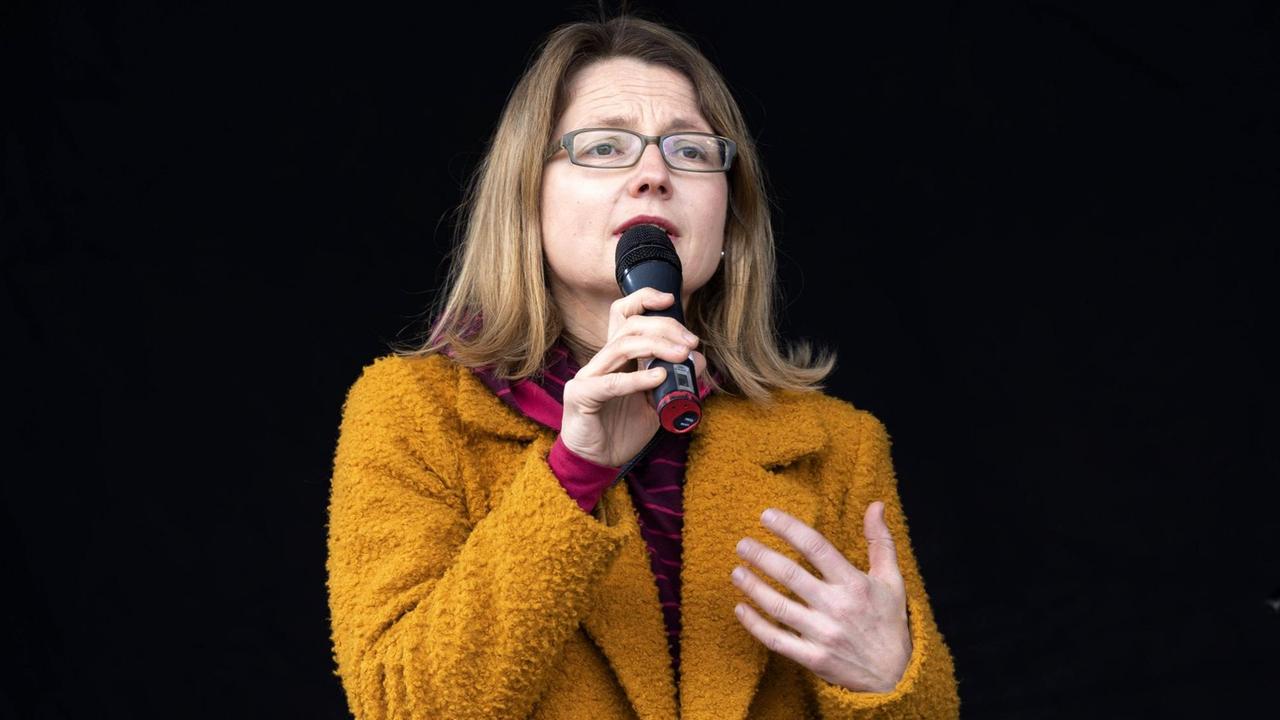 Die Dresdener Kulturbürgermeisterin Annekatrin Klepsch mit Brille und orangener Jacke spricht in ein Mikrofon.