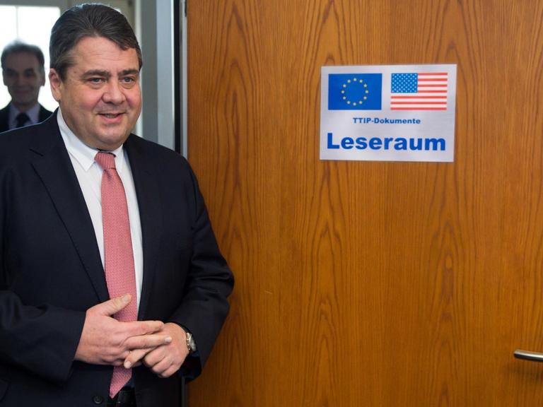 Bundeswirtschaftsminister Sigmar Gabriel (SPD) vor einer Holztür mit der Aufschrift "Leseraum" und der US- und EU-Flagge.