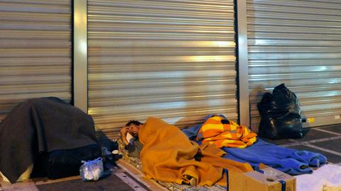 Ein Obdachloser liegt auf seinem Schlafplatz auf dem Bürgersteig vor einer Filiale der Emporiki Bank in Athen