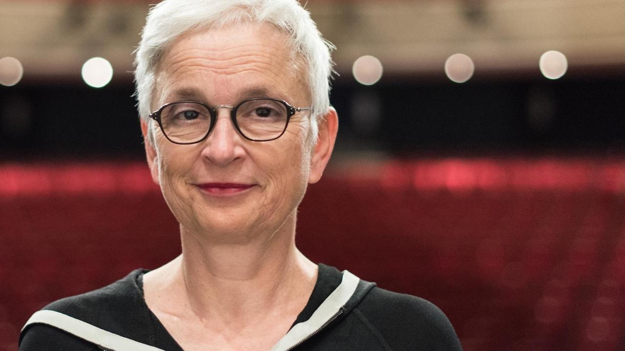 Barbara Mundel steht im Theater Freiburg und trägt kurze Haare und eine schwarze Brille Barbara Mundel steht im Theater Freiburg und trägt kurze Haare und eine schwarze Brille
