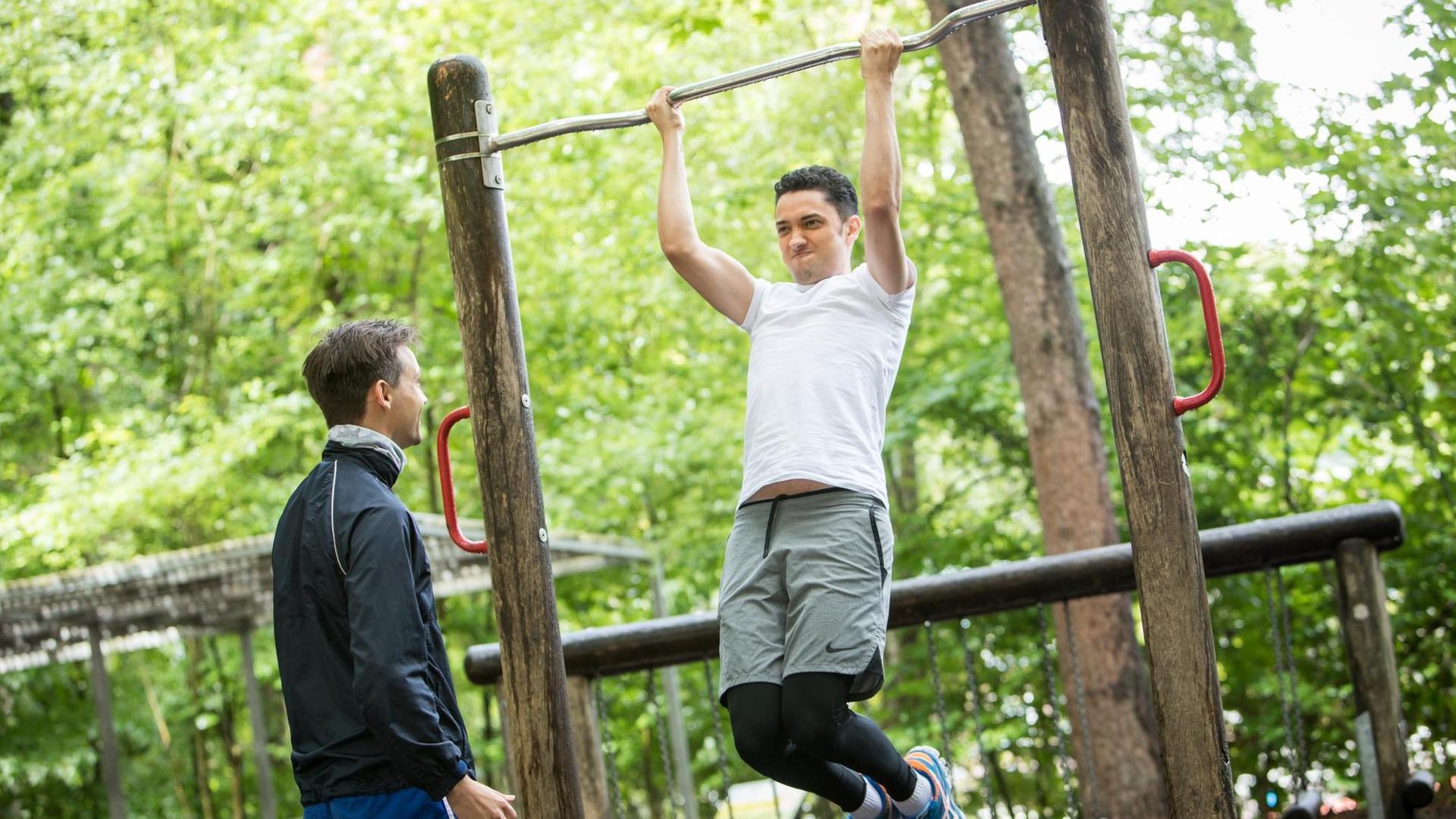 Zwei Männer trainieren in einem Park mit Sportgeräten. Zwei Männer trainieren in einem Park mit Sportgeräten.