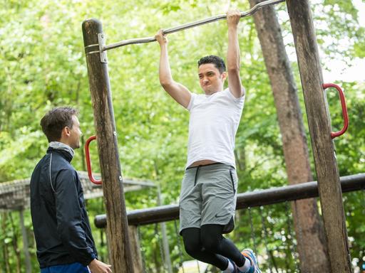Zwei Männer trainieren in einem Park mit Sportgeräten.