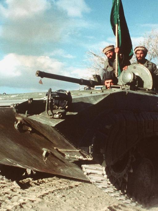 Panzer, auf dem drei Männer sitzen und eine grüne Fahne hissen