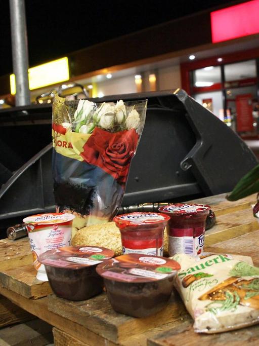Eine Frau wühlt in einem Container nach weggeworfenen Lebensmitteln