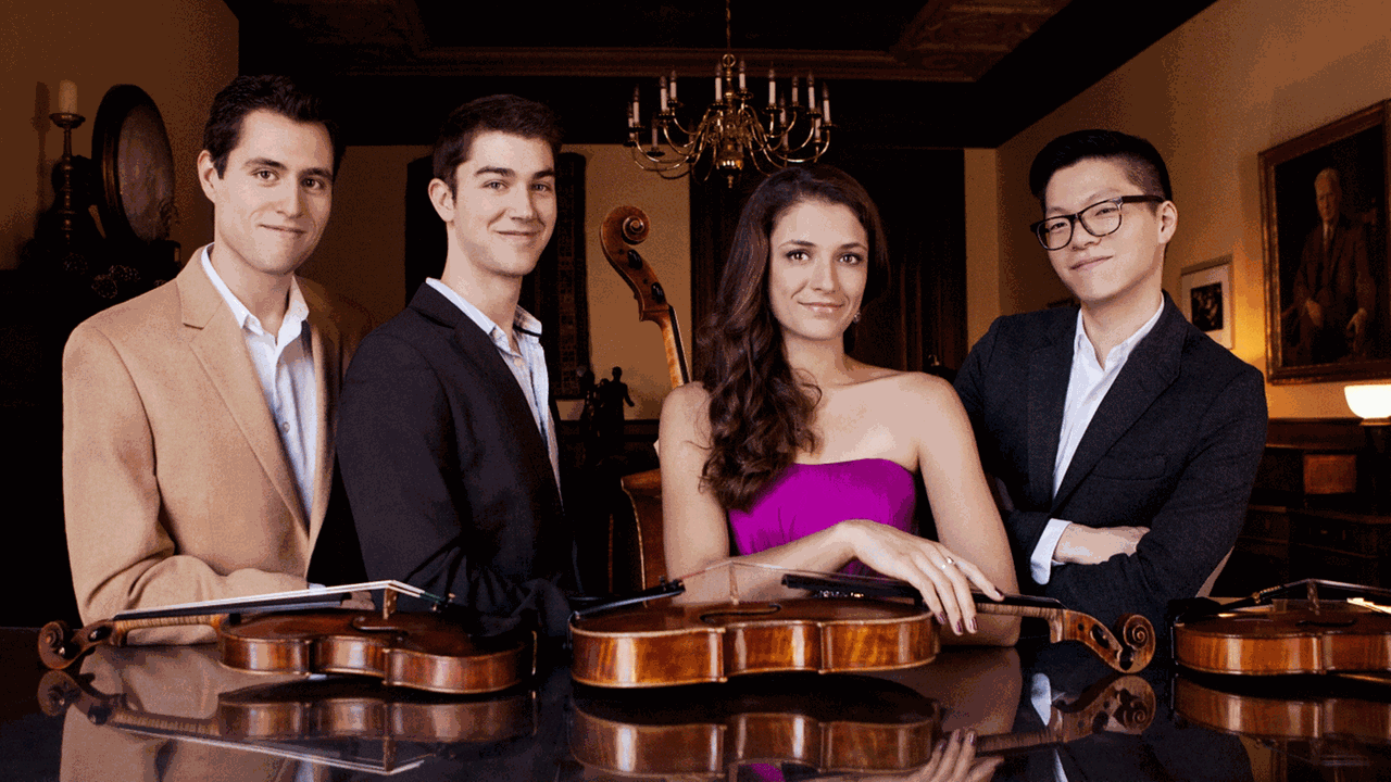 Die Mitglieder des Dover Quartets aus den USA im Halbporträt lächeln in die Kamera und haben die Violinen und die Viola vor sich auf dem glänzenden Deckel eines Klavierflügels liegen. Die Mitglieder des Dover Quartets aus den USA im Halbporträt lächeln in die Kamera und haben die Violinen und die Viola vor sich auf dem glänzenden Deckel eines Klavierflügels liegen.