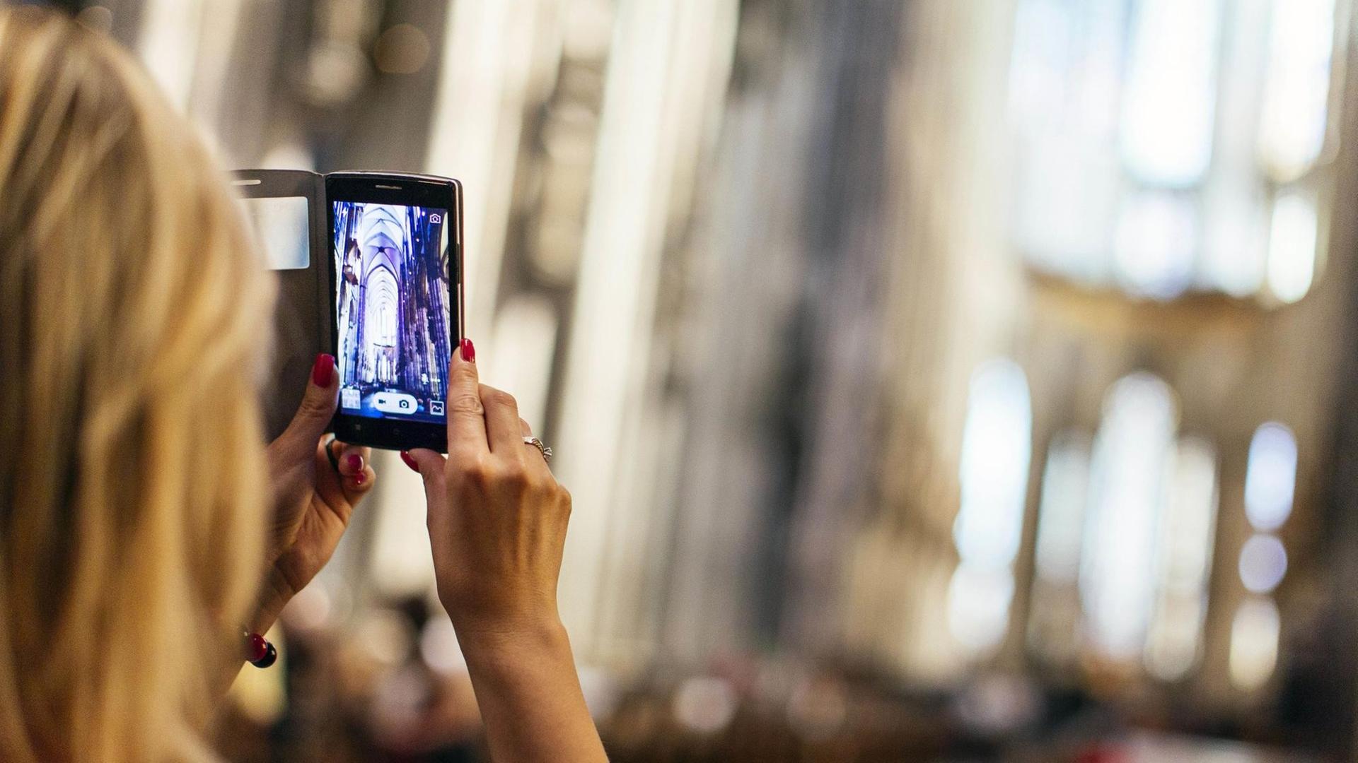 Eine Touristin macht ein Handyfoto im Inneren des Kölner Doms. Eine Touristin macht ein Handyfoto im Inneren des Kölner Doms.