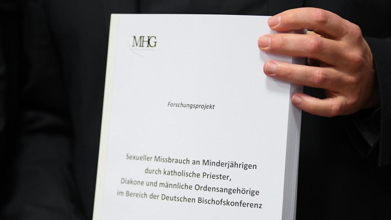 25.09.2018, Hessen, Fulda: Stephan Ackermann, Bischof von Trier und Beauftragter für Fragen des sexuellen Missbrauchs im kirchlichen Bereich, hält zu Beginn einer Pressekonferenz der Deutschen Bischofskonferenz ein Exemplar der Studie "Sexueller Missbrauch an Minderjährigen durch katholische Priester, Diakone und männliche Ordensangehörige im Bereich der Deutschen Bischofskonferenz". Die lange erwartete Studie ist der wichtige Tagesordnungspunkt des viertägigen Treffens der deutschen Bischöfe in der osthessischen Domstadt. Foto: Arne Dedert/dpa | Verwendung weltweit 25.09.2018, Hessen, Fulda: Stephan Ackermann, Bischof von Trier und Beauftragter für Fragen des sexuellen Missbrauchs im kirchlichen Bereich, hält zu Beginn einer Pressekonferenz der Deutschen Bischofskonferenz ein Exemplar der Studie "Sexueller Missbrauch an Minderjährigen durch katholische Priester, Diakone und männliche Ordensangehörige im Bereich der Deutschen Bischofskonferenz". Die lange erwartete Studie ist der wichtige Tagesordnungspunkt des viertägigen Treffens der deutschen Bischöfe in der osthessischen Domstadt. Foto: Arne Dedert/dpa | Verwendung weltweit