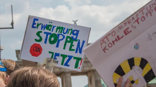Demonstration der "Friday for Future"-Bewegung in Berlin: Im Hintergrund ist das Brandenburger Tor zu sehen, im Vordergrund wird ein Schild mit der Aufschrift "Erwärmung stoppen jetzt" hochgehalten.